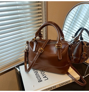 Macro detail of dark brown leather pillow bag with gold hardware and fine stitching