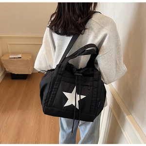 Vista laterale di una borsa tote in nylon nero con stampa stella e coulisse