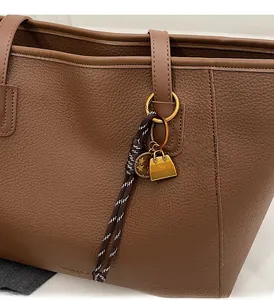 Close-up detail of litchi grain leather tote bag with stylish metallic star charms