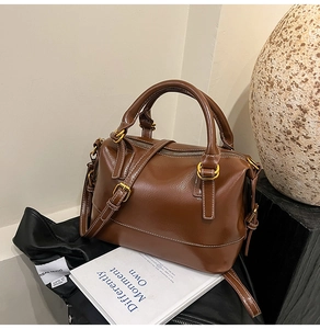 Detail view of brown leather Boston bag with white contrast stitching and gold hardware
