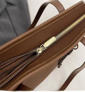Detailed macro view of smooth gold zipper and brown litchi texture on tote bag