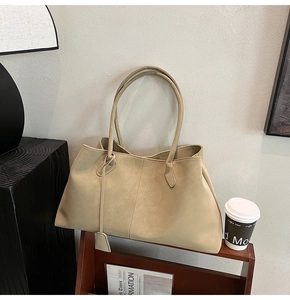 Large beige tote bag displayed on a wooden shelf with cozy modern lifestyle decor