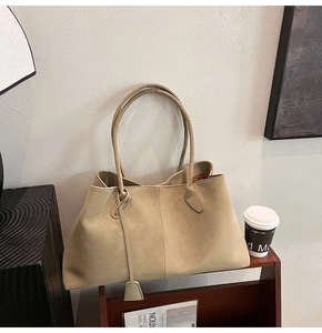 Detail of khaki frosted leather tote bag with long handles and a triangle pendant decoration