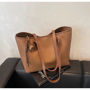 Detailed macro of brown pebble leather tote bag with gold lock and braided rope decor