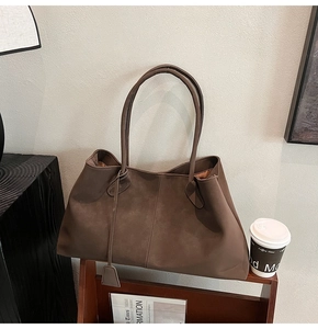 Macro detail of large matte tote bag with vertical stitching and square pendant detail