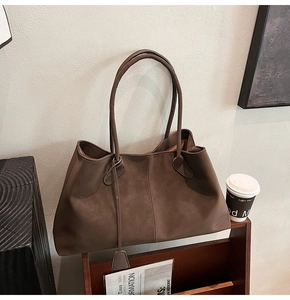 Detail of a large dark brown matte tote bag with shoulder strap in an elegant setting