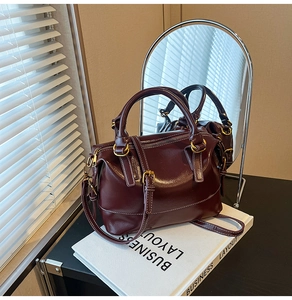 Detail of burgundy leather Boston bag on business layout book with mirror reflection