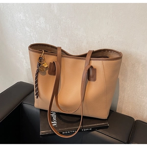 Detail of beige lychee grain leather tote bag with brown straps and star charm