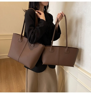 Close-up of dual brown pebbled leather tote bags set with sleek stitching and slim straps