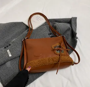 Detalle de bolso tote de cuero marrón con ribete de borreguito y parche de flor