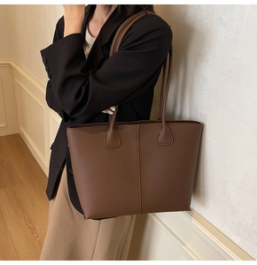 Deep brown pebble leather tote bag with vertical stitching and slim straps on a model