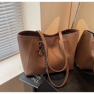 Close-up of coffee brown tote bag featuring litchi texture and golden ring accessory