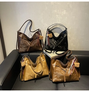 Four vintage hobo tote bags in black and brown shades displayed on a black leather sofa