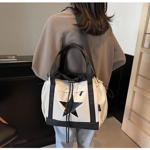 Dettaglio della grande borsa tote con stella e coulisse nera mostrata sulla spalla