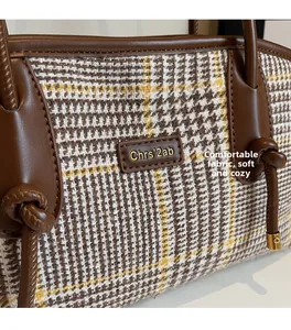 Nahaufnahme von weichem Karostoff und braunem Lederbesatz an der Vintage-Handtasche