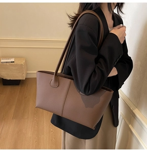 Brown litchi grain leather tote bag worn by a model in professional office attire