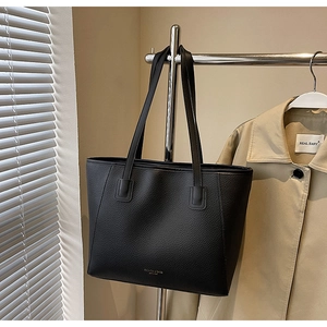 Detail shot of black pebbled leather tote bag with long handles and fashion text