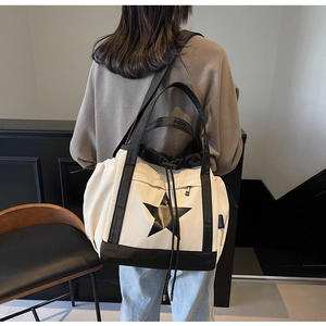 Dettaglio della grande borsa tote in tela con stella nera e chiusura a coulisse sulla spalla