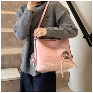 Detalle de bolso tote de cuero rosa claro con ribete de piel sintética y lazo decorativo