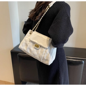Close-up of quilted white leather shoulder bag with golden chain and metal lock detail