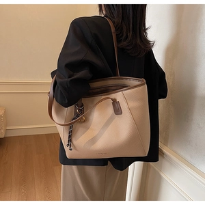 Detail view of large tote bag in beige pebbled leather with brown contrast trim
