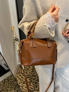 Brown vintage Boston bag with white stitching and leather texture worn on wool coat