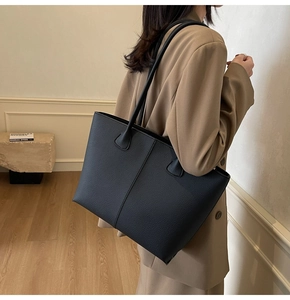 Detail of black pebbled leather tote bag showing grainy texture and sturdy double handles