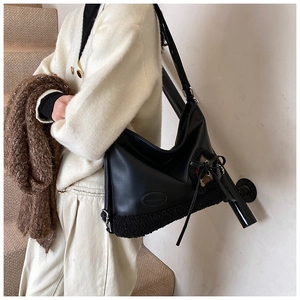 Detalle del bolso tote negro con panel de piel sintética y elegante lazo decorativo