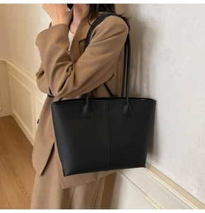Detailed texture of black lychee grain faux leather on a large commuter tote bag