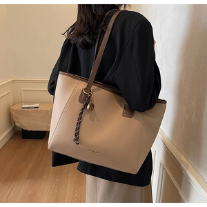 Close-up of beige lychee leather tote bag with dark brown straps and metal detail