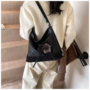 Detalle del bolso tote de PU negro con ribete de piel sintética y lazo en una modelo