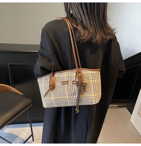 Detailansicht der Hahnentritt-Tasche mit braunen Ledergriffen, getragen von einem Modell