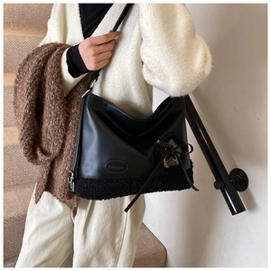Detalle del bolso tote de cuero negro con ribete de pelo sintético y adorno de lazo
