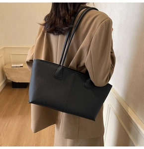 Close-up of black leather tote bag featuring rich lychee texture and vertical stitching