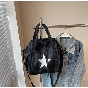 Dettaglio della borsa tote in nylon nero con coulisse, stampa stella e tasche
