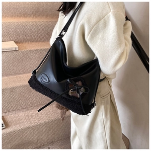 Detalle del bolso tote negro con ribete de sherpa, lazo y parche de cuadros