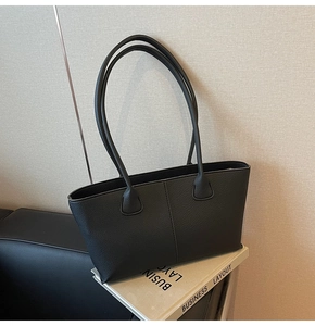Detailed view of the black pebble leather texture and stitching on this tote bag
