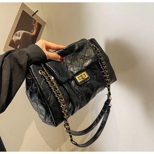 Detail of black quilted leather shoulder bag featuring gold chain and metal lock