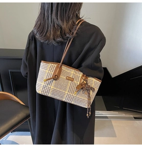 Detailansicht der Hahnentritt-Tasche mit braunem Lederbesatz und Quastenanhänger