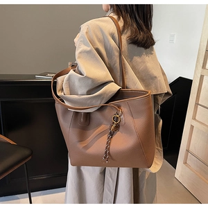 Close-up of brown litchi pattern leather tote bag with stylish braided rope charm