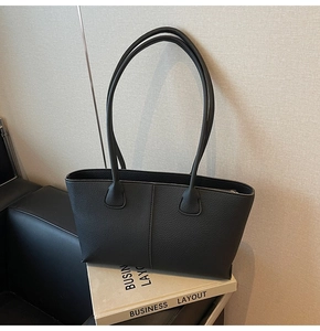 Close-up of black lychee grain leather texture and stitching on minimal tote bag