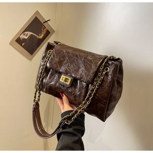 Detail of dark brown quilted leather crossbody bag with vintage gold-tone chain and lock