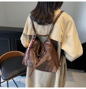 Detail of dark brown retro leather backpack with metal buckles and plush bear pendant