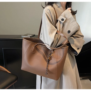 Detail of coffee brown pebble leather tote bag featuring elegant brand text engraving