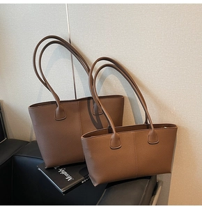 Detail of dark brown pebble leather tote bag set with vertical stitching on leather sofa
