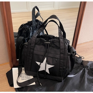 Dettaglio della borsa tote in nylon nero con stella, coulisse e tracolla regolabile