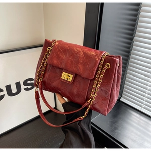 Detail of dark red quilted leather crossbody bag with golden chain and twist lock clasp