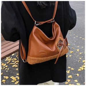 Detalle de una mochila de cuero marrón con ribete de vellón y un lazo decorativo en otoño
