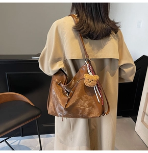 Macro view of brown leather tote bag texture with long fringe and bear charm detail