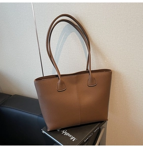 Detailed view of caramel brown lychee leather tote bag with vertical seam and sturdy handle